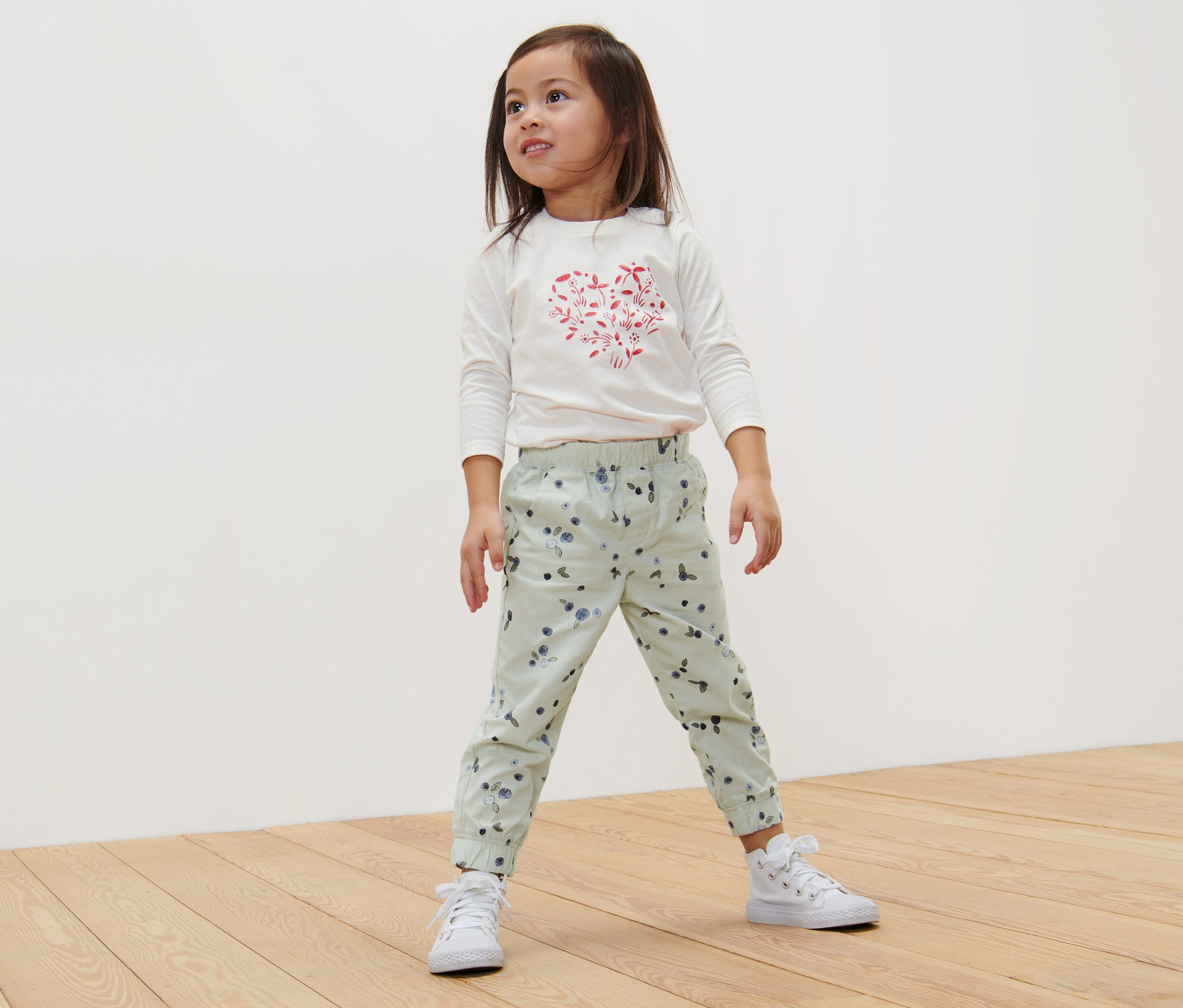 Mädchen steht auf Holzboden und trägt eine Kinder-Pull-on-Pants – Fit »Ella«, Beeren.