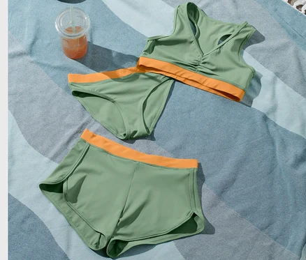 Ein Kinder-Bikini-Set, 3-teilig, ein Getränk und eine Strandtasche liegen auf einem Strandtuch.
