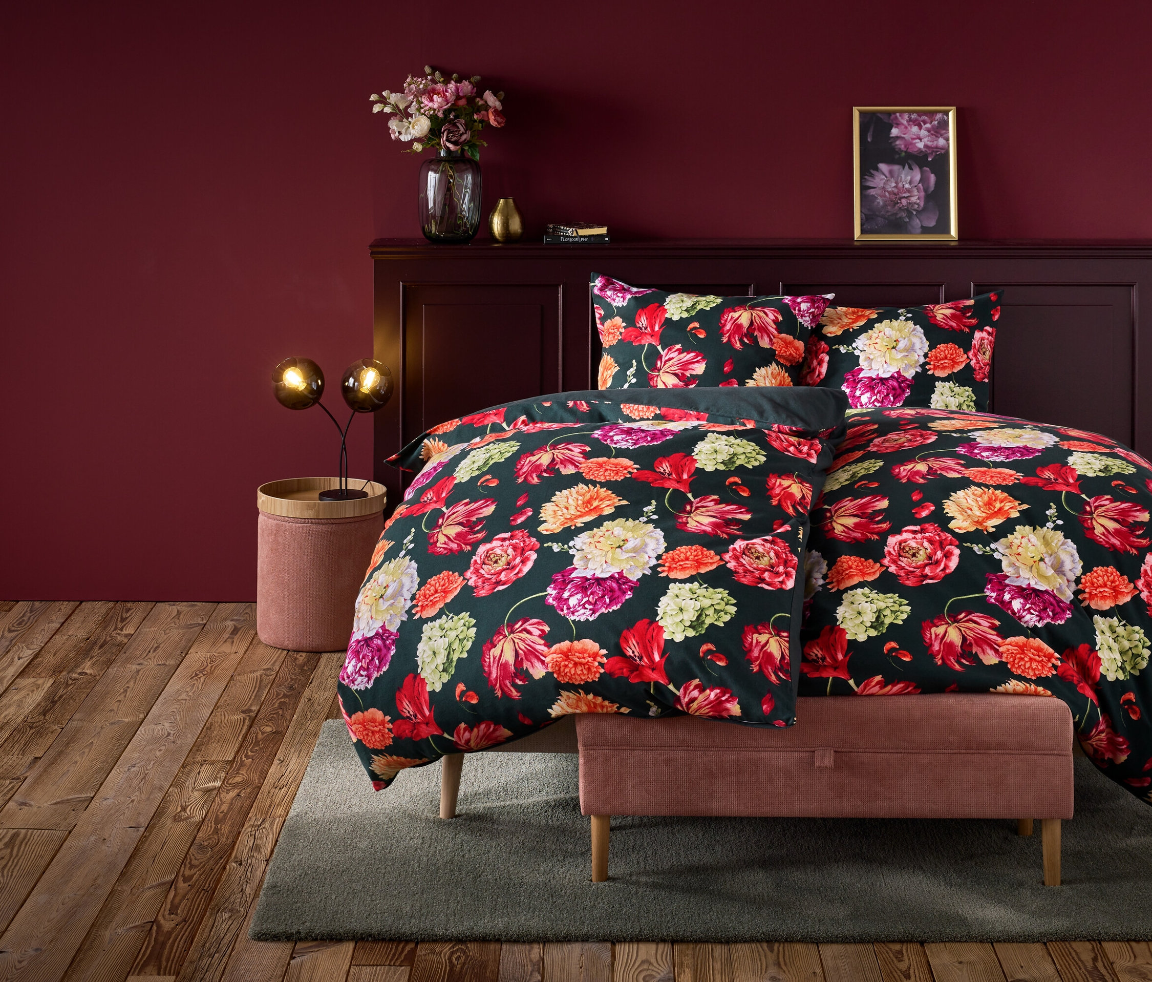 Blumenbettwäsche auf einem Bett in einem weinrot gestrichenen Zimmer.