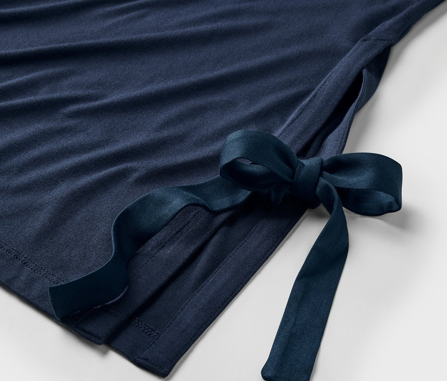 Detailansicht eines marineblauen Kleides mit Schleife an der Seite.