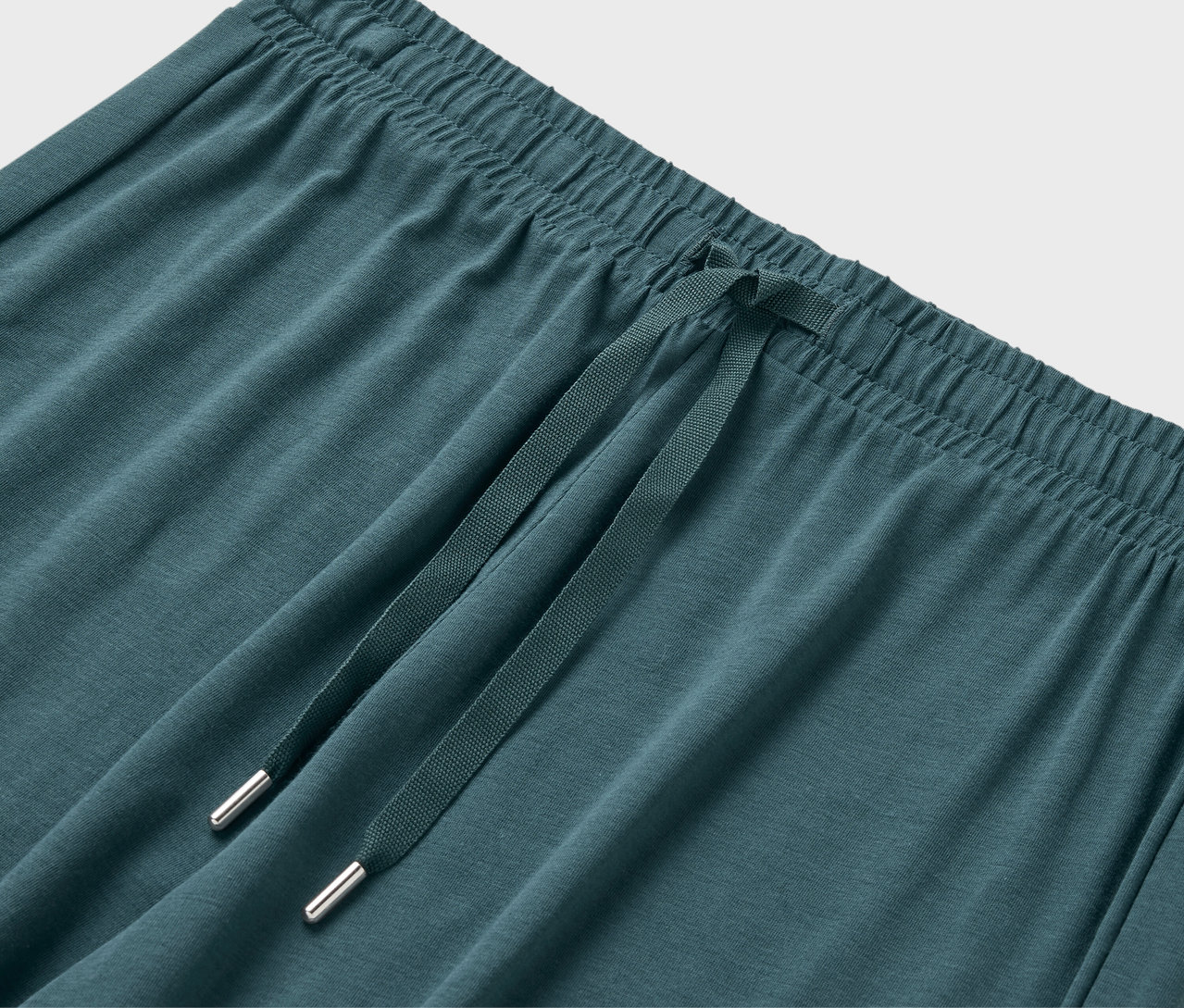 Nahaufnahme der elastischen Taille und des Kordelzugs einer blaugrünen Jogginghose.