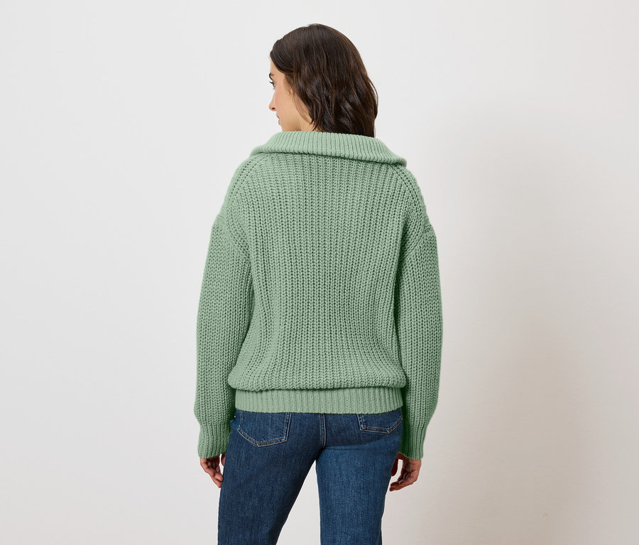 Frau in grünem Pullover blickt nach links.