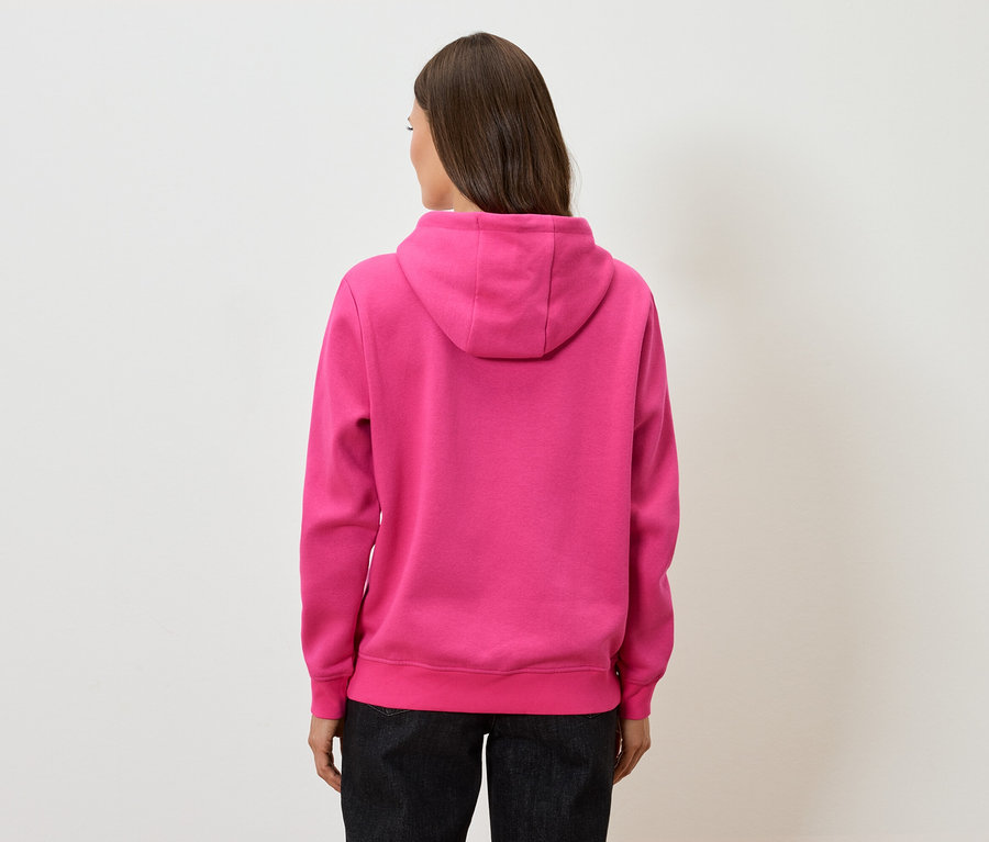 Rückansicht einer Frau mit braunen Haaren in einem pinkfarbenen Hoodie und einer schwarzen Hose.