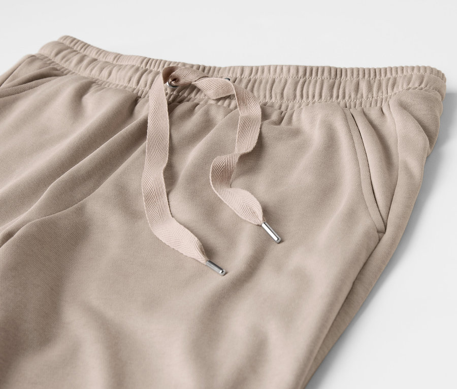 Detailaufnahme einer beigen Jogginghose mit Kordelzug und Tasche.