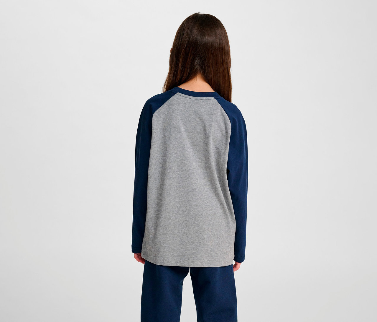 Rückansicht eines Mädchens, das ein blaues HUMMEL HMLJR Raglan Loose T-Shirt BEE trägt.