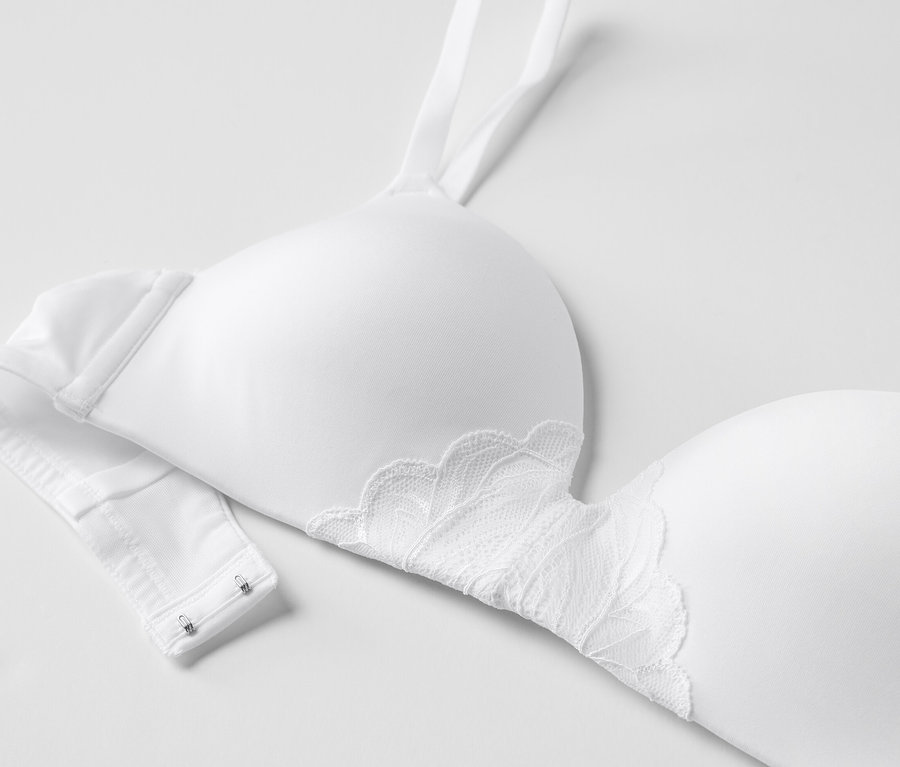 Detailansicht eines weißen Softschalen-BHs mit Spitze auf weißem Hintergrund.