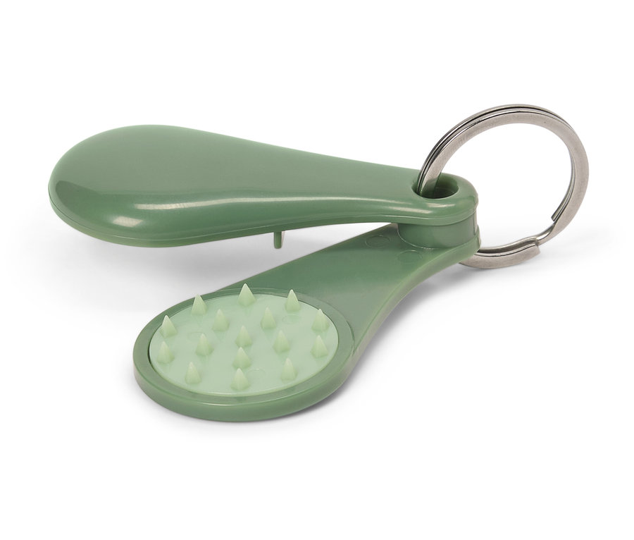 Ein grüner Massage-Schlüsselanhänger liegt auf einem weißen Hintergrund.