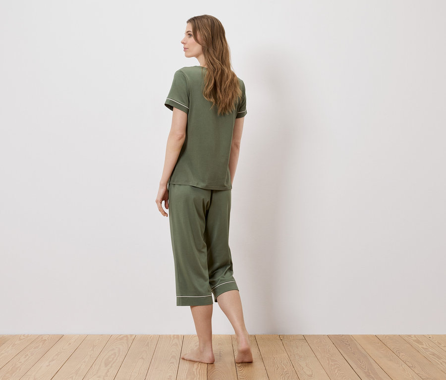 Frau von hinten, die einen grünen Pyjama mit weißer Paspelierung trägt.