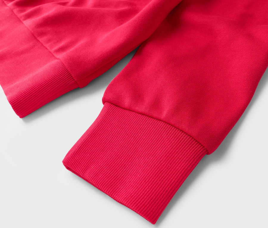 Nahaufnahme von Ärmeln eines roten Pullovers mit gerippten Bündchen auf weißem Hintergrund.