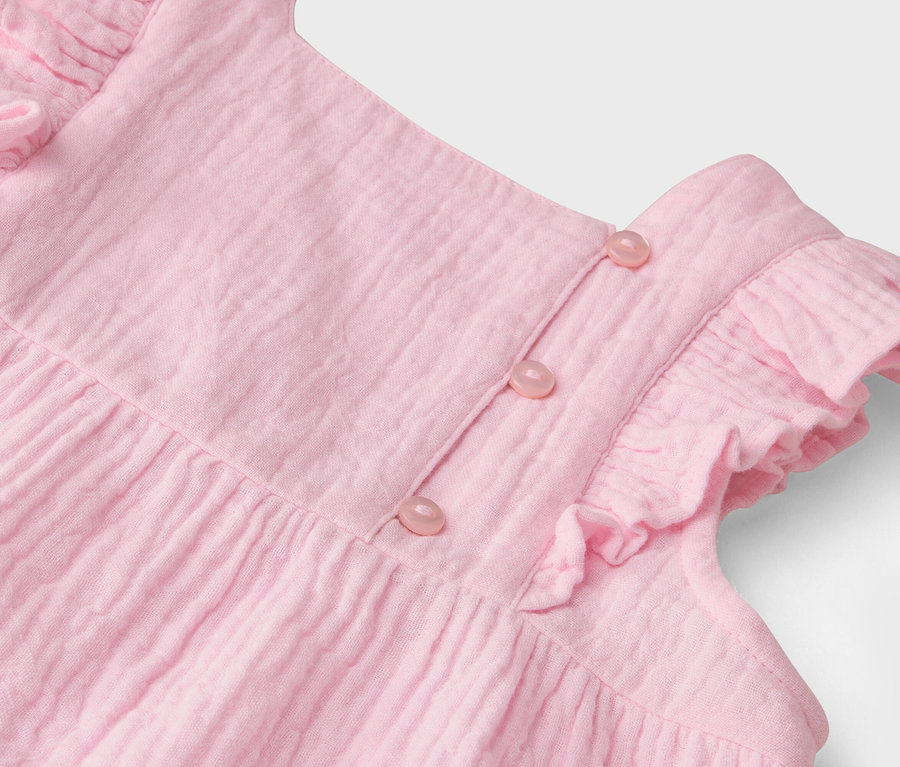 Detailaufnahme eines rosa Kleides mit Rüschen und Knöpfen.