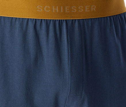 Blaue Schlafhose mit braun-goldenem Bund, auf dem das „SCHIESSER“-Logo zu sehen ist.
