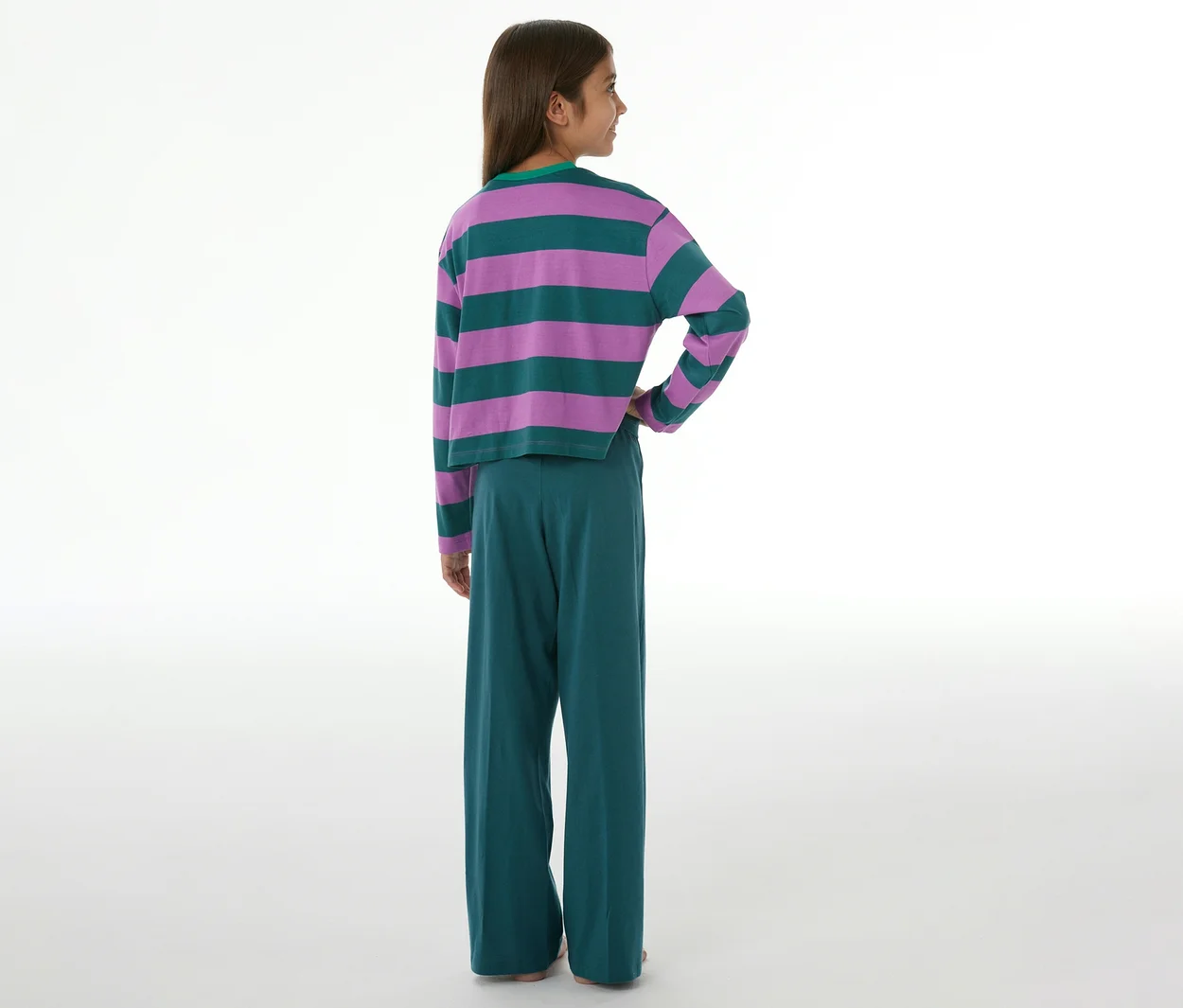 Kind von hinten, das einen SCHIESSER Kinder-Pyjama trägt, bestehend aus einem lila-grün gestreiften Langarmshirt und einer grünen Hose mit weitem Bein.
