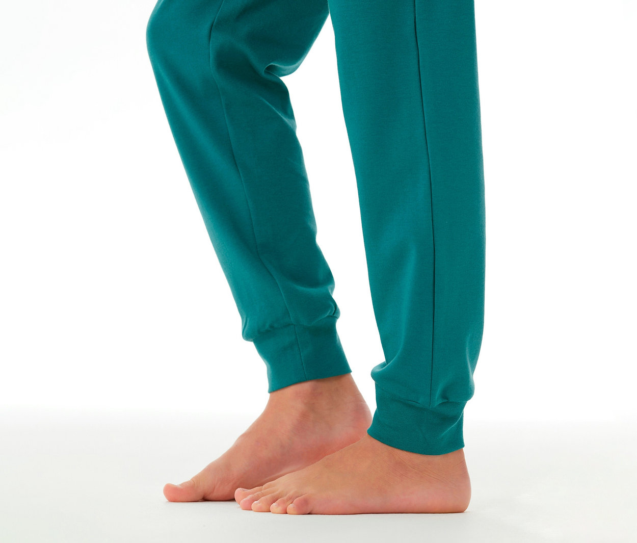 Kinderfüße und Unterschenkel in einer tealfarbenen SCHIESSER Kinder-Interlock-Pyjamahose mit Bündchen.