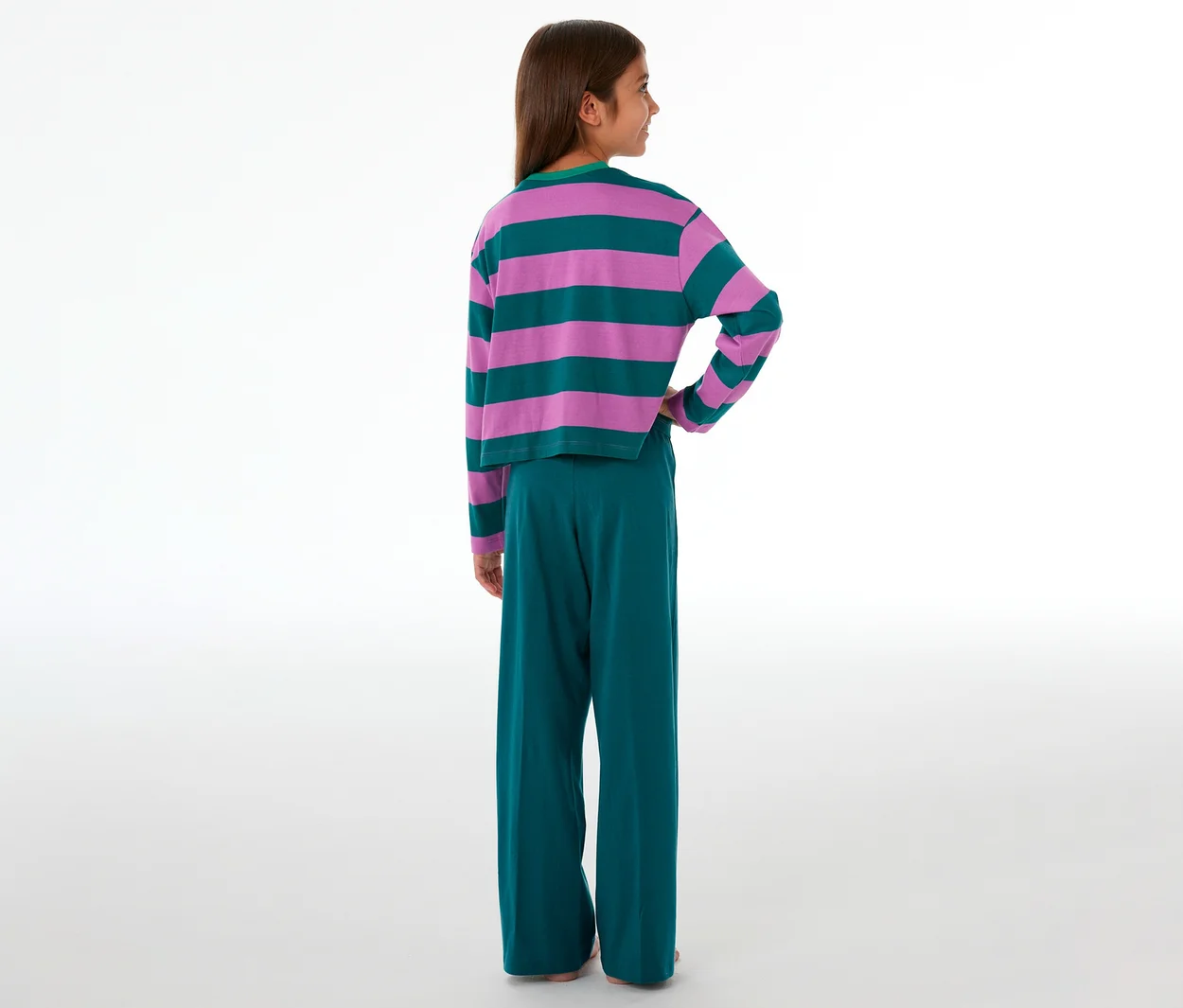 Mädchen von hinten in einem SCHIESSER Kinder-Pyjama mit pink-grün gestreiftem Oberteil und grüner Hose.