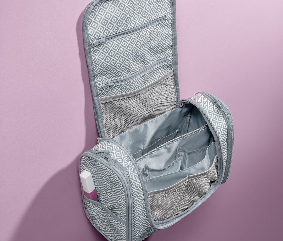Geöffnete, graue Kulturtasche zum Aufhängen mit geometrischem Muster.
