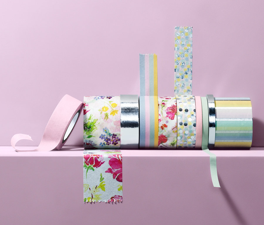 Auf hellviolettem Hintergrund liegen 10 Deko-Klebebänder auf einem hellvioletten Regal.