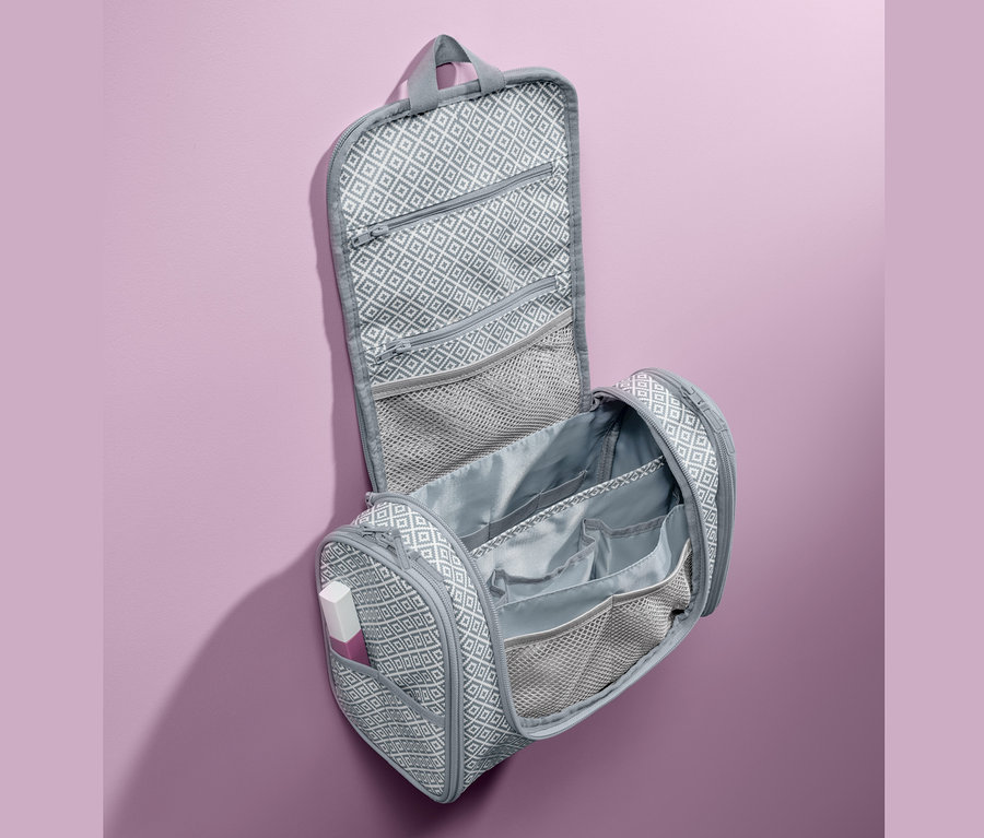 Geöffnete, graue Kulturtasche zum Aufhängen mit geometrischem Muster.