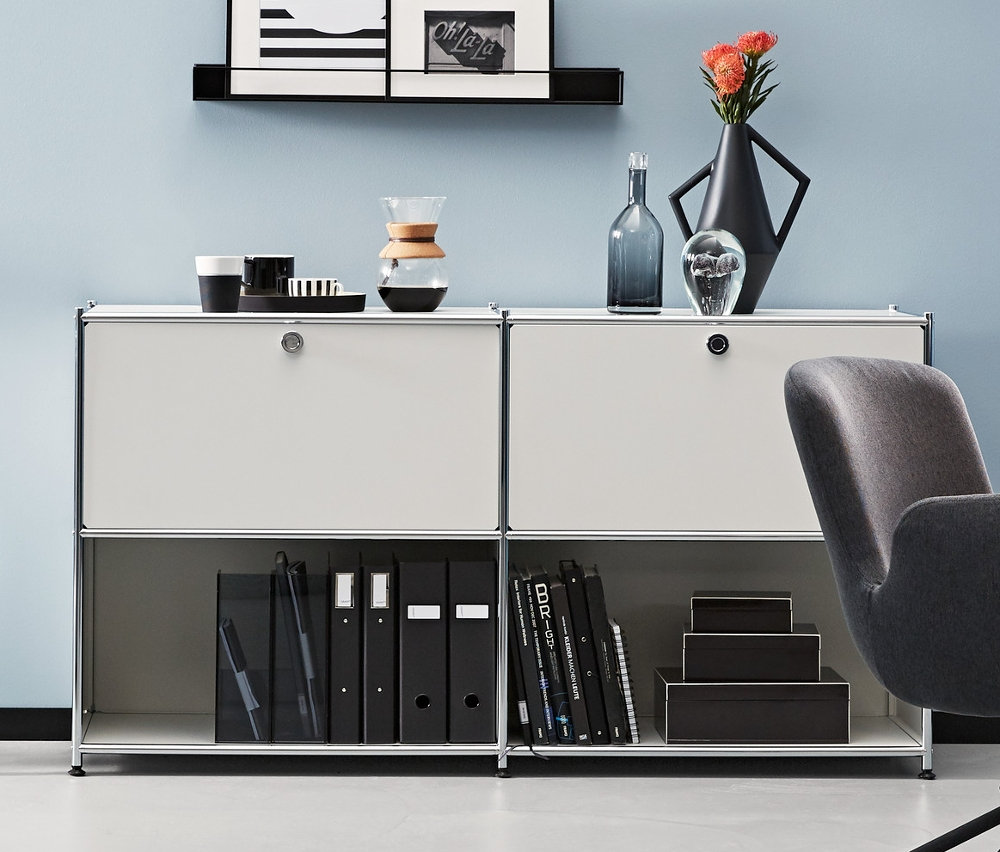 Ein Zimmer mit einem anthrazitfarbenen Schreibtischstuhl und Metall-Sideboards. Ein anthrazitfarbenes und zwei weiße Metall-Sideboards CN3 mit 2 versetzbaren Klappenfächern.