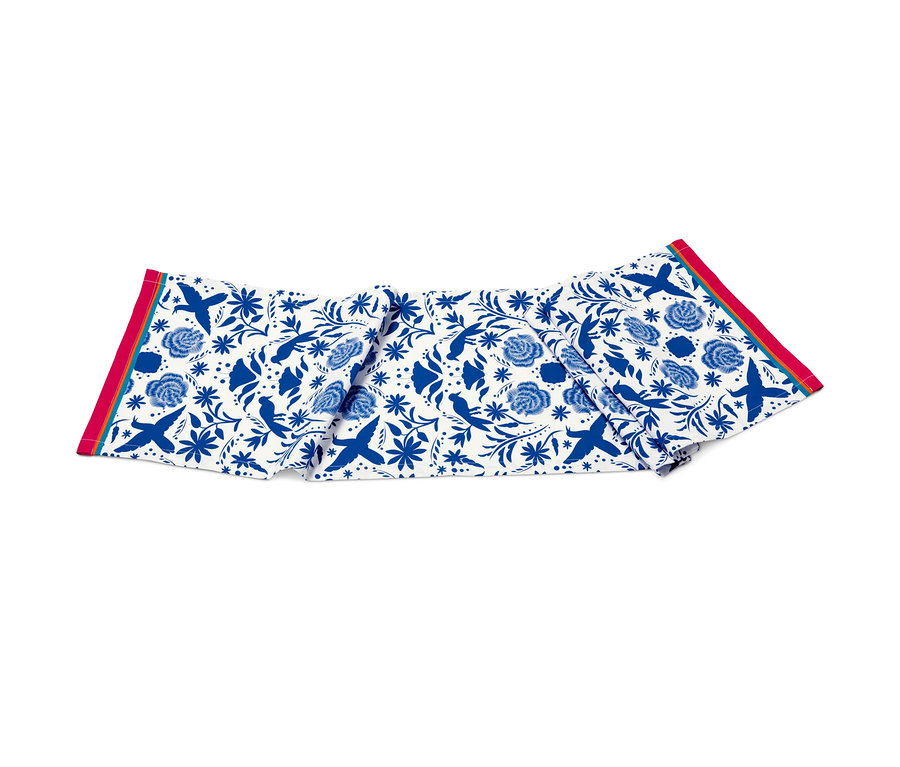 Ein Tischläufer mit blauem Blumen- und Vogelmuster.