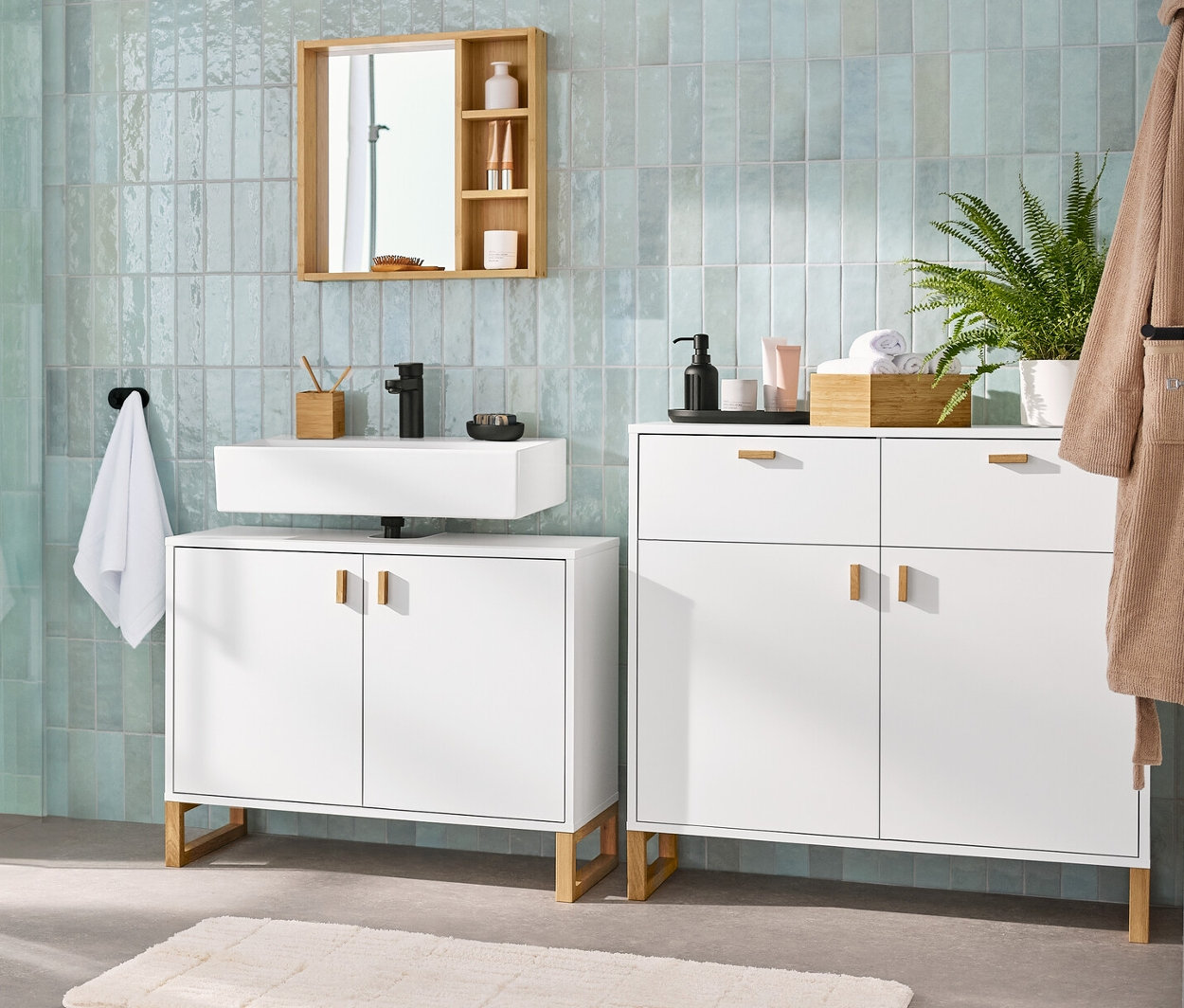 Ein Badezimmer-Interieur mit einem Waschbeckenunterschrank mit 2 Türen, einem Spiegel mit Ablageflächen, einem Sideboard mit 2 Schubladen und 2 Türen und einem Bad-Hochschrank.