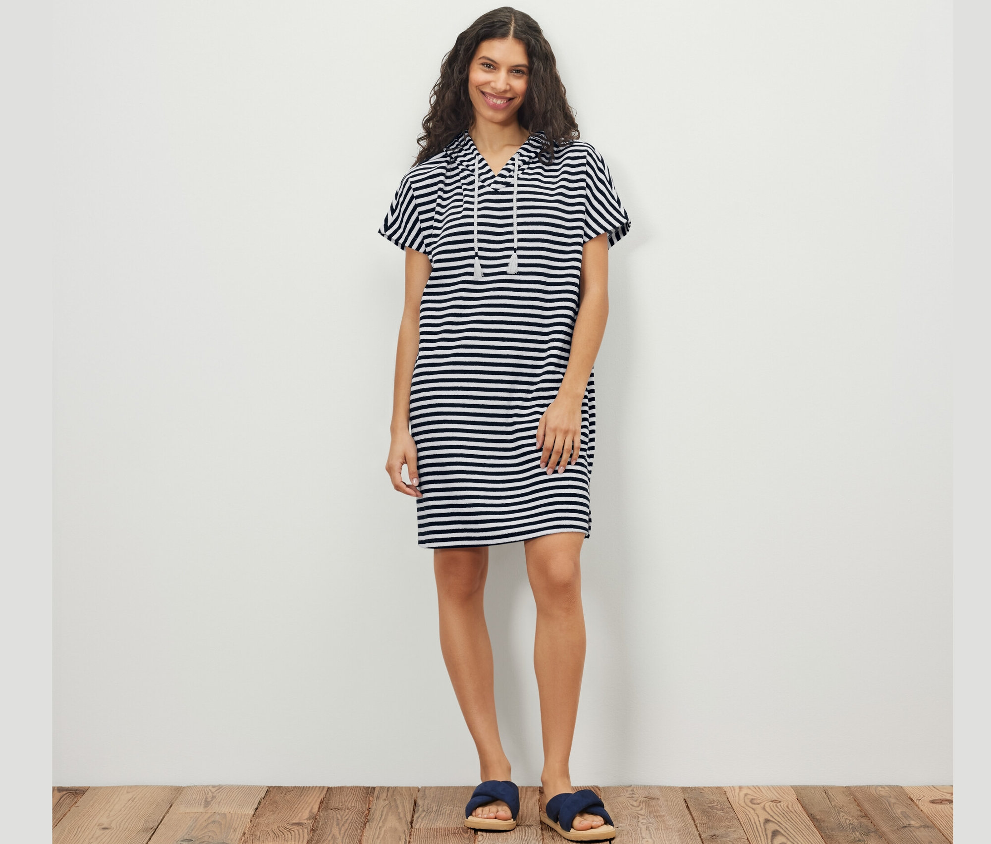 Frau posiert in gestreiftem Frottee-Strandkleid.