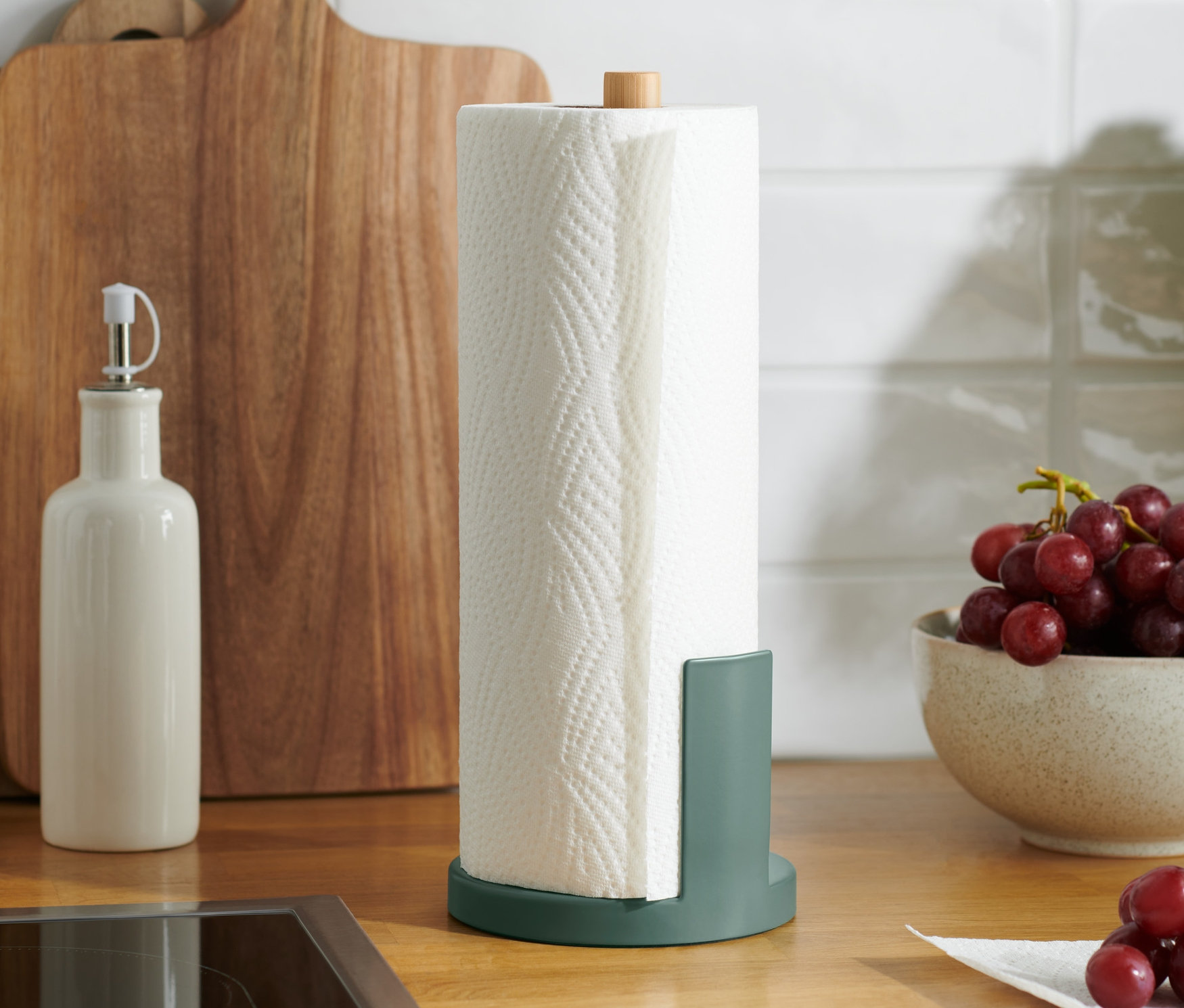 Auf einer Küchentheke steht ein Küchenrollenhalter neben einer Schale mit Weintrauben.
