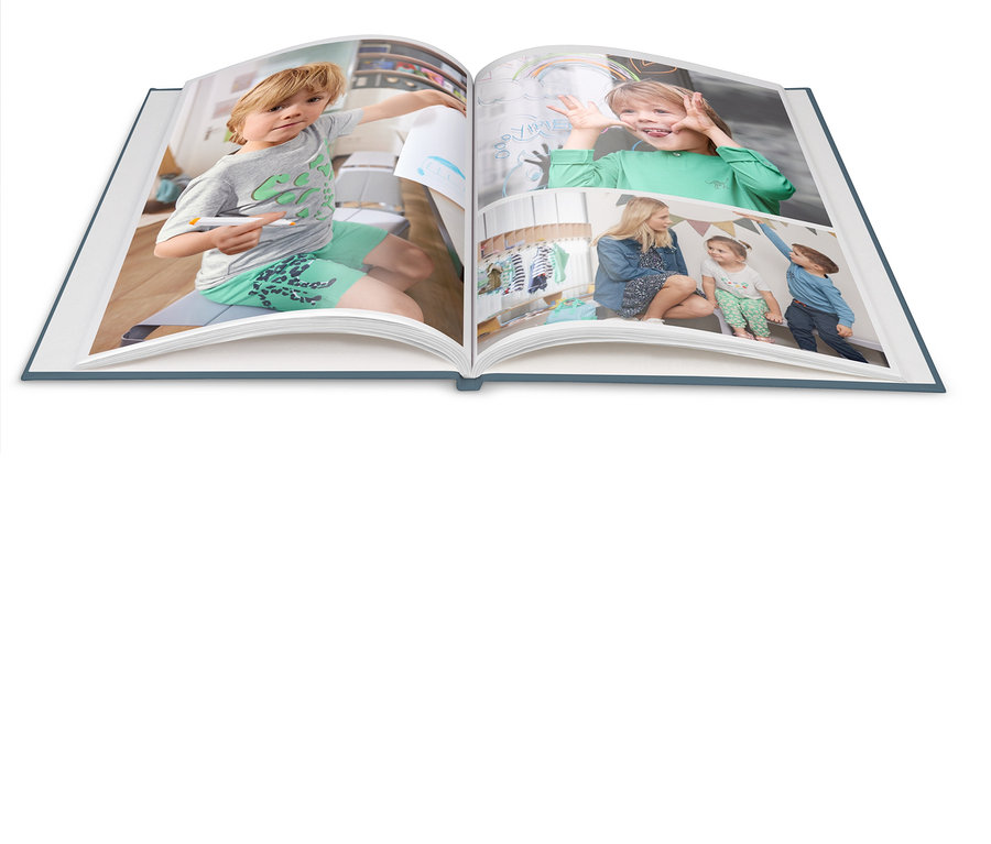 Ein geöffnetes Fotobuch zeigt einen Jungen, der mit einem Marker zeichnet, einen Jungen, der Grimassen schneidet, und eine Frau mit Kindern, die unter einem Zelt sitzen.