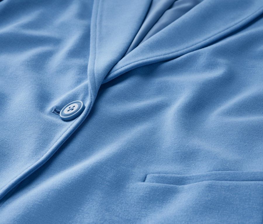 Detailansicht eines hellblauen Jerseyblazers mit Knopf und Tasche.