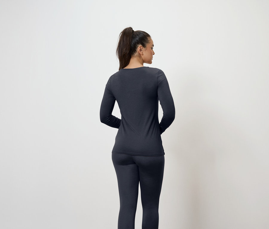 Frau mit Pferdeschwanz trägt ein dunkelblaues Langarmshirt und Leggings, von hinten gesehen.