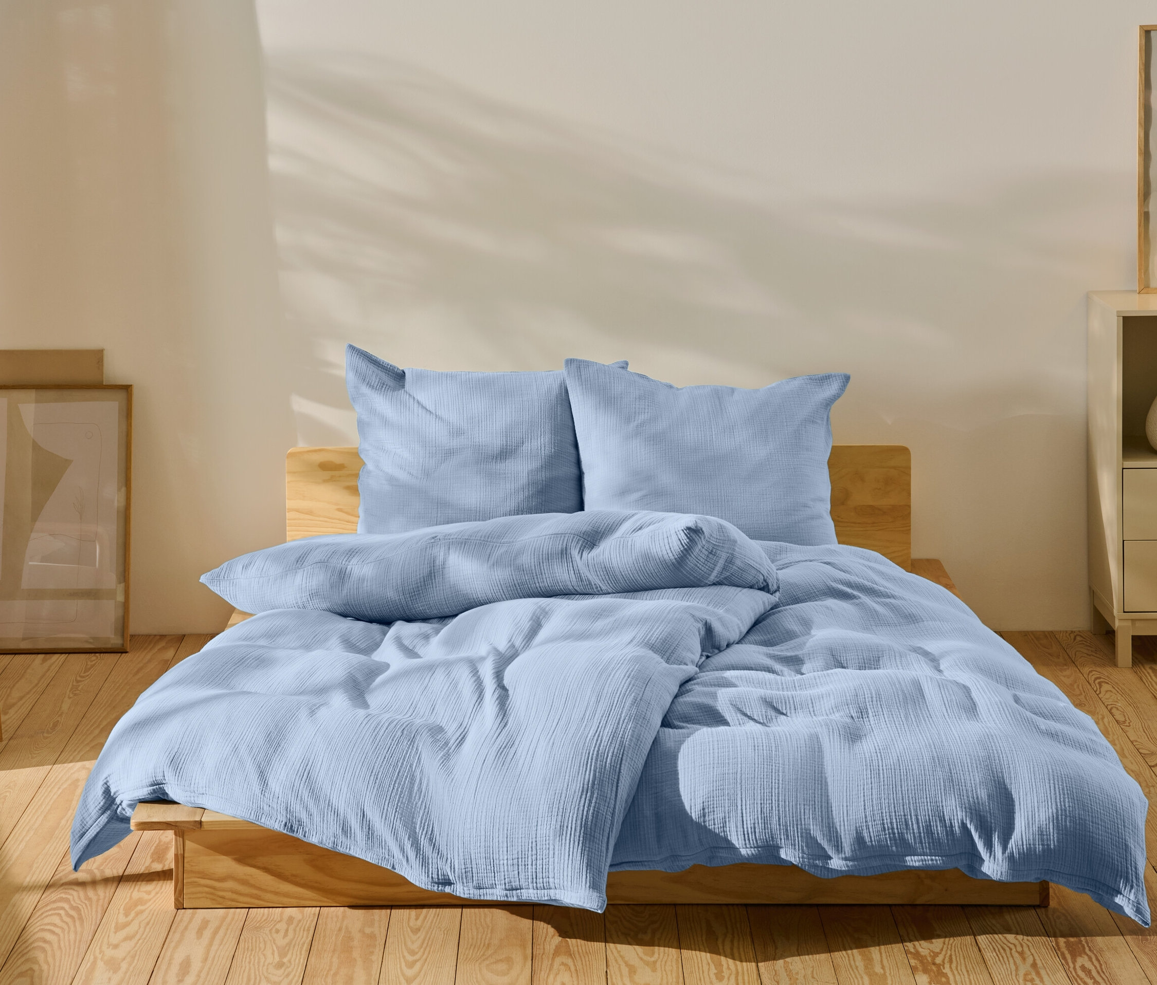 Hellblaue Bettwäsche auf einem Bett in einem Schlafzimmer.