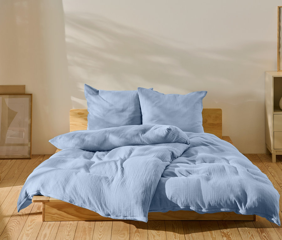 Hellblaue Bettwäsche auf einem Bett in einem Schlafzimmer.