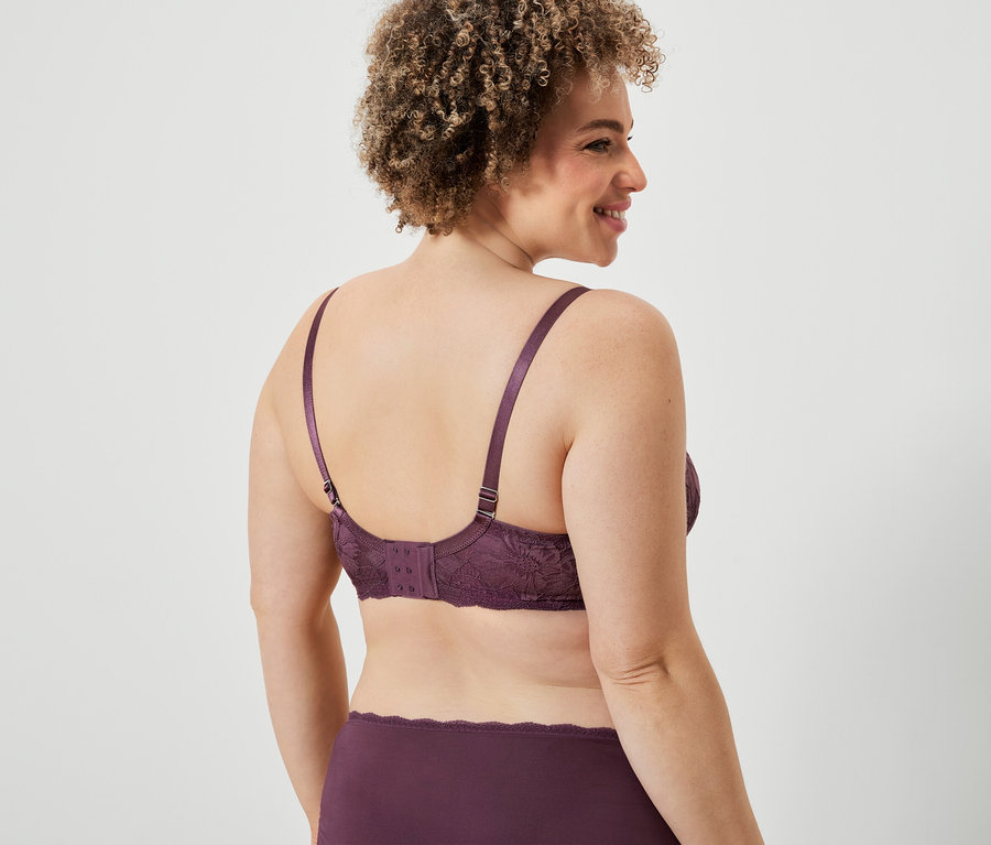 Frau trägt bordeauxfarbenen Spitzen-BH und Höschen, Rückansicht.