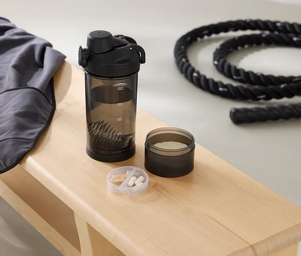 Auf einer Bank liegen ein graues Sweatshirt, eine Trinkflasche, eine Dose mit Pulver und ein Seil.