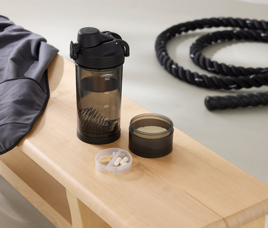 Auf einer Bank liegen ein graues Sweatshirt, eine Trinkflasche, eine Dose mit Pulver und ein Seil.