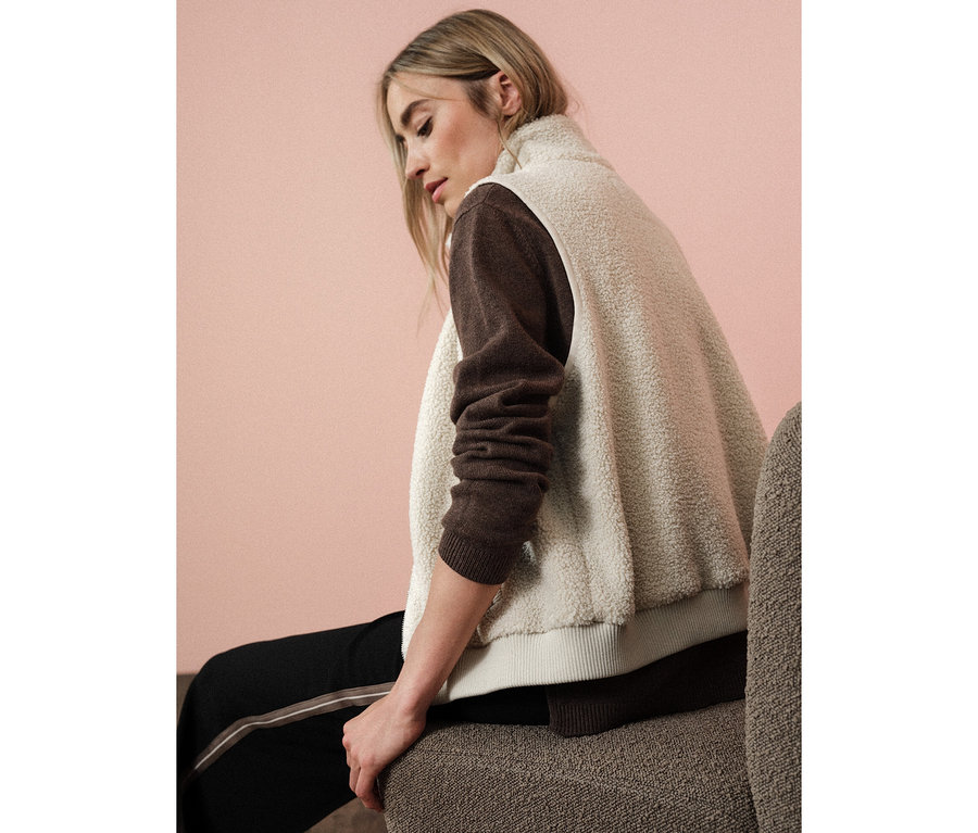Frau sitzt und trägt eine Street One Teddyweste über einem braunen Pullover.