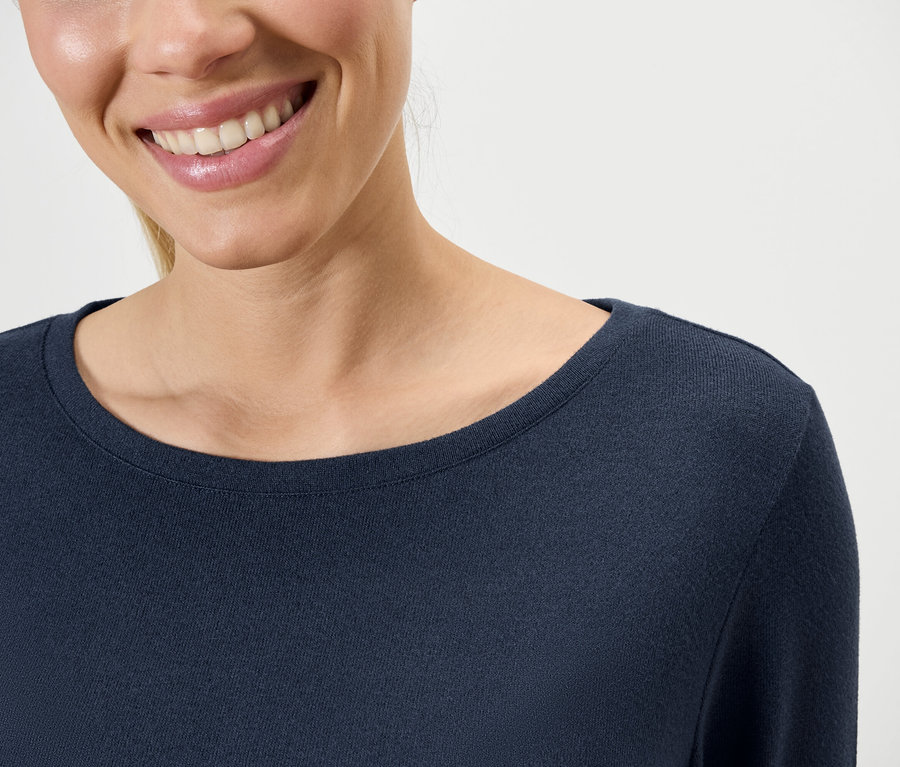 Lächelnde Frau trägt ein dunkelblaues Langarmshirt.