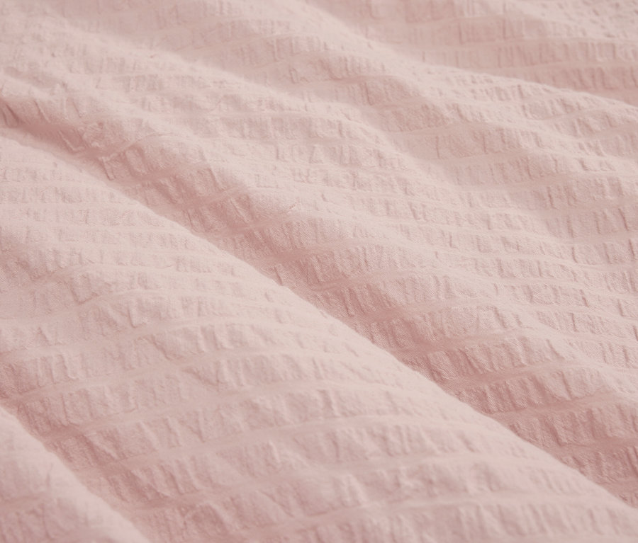 Nahaufnahme eines hellrosa Stoffes mit Textur.