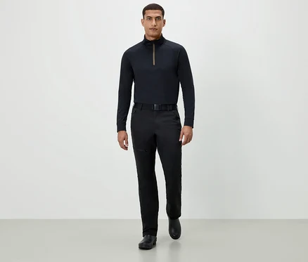 Ein Mann geht in einem schwarzen Langarmshirt, schwarzen Hosen und schwarzen Schuhen vorwärts.