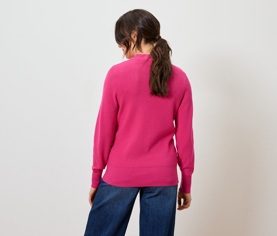 Rückansicht einer Frau mit pinkem Pullover und blauen Jeans.