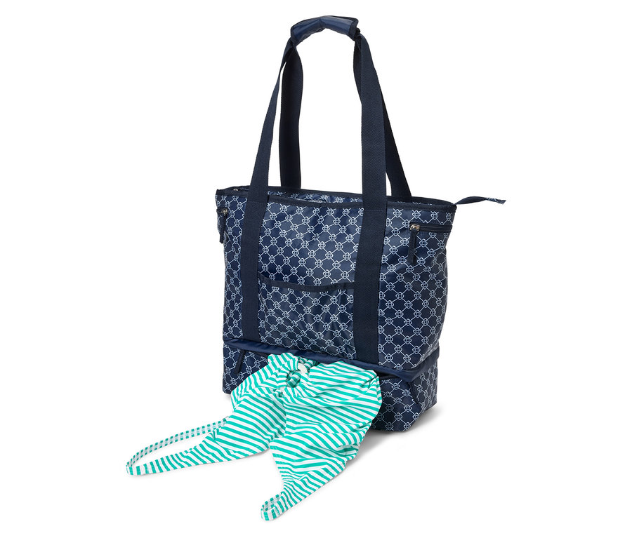 Marineblaue Tragetasche mit weißem Muster und marineblauen Henkeln. Ein gestreiftes Kleidungsstück hängt aus dem unteren Fach.