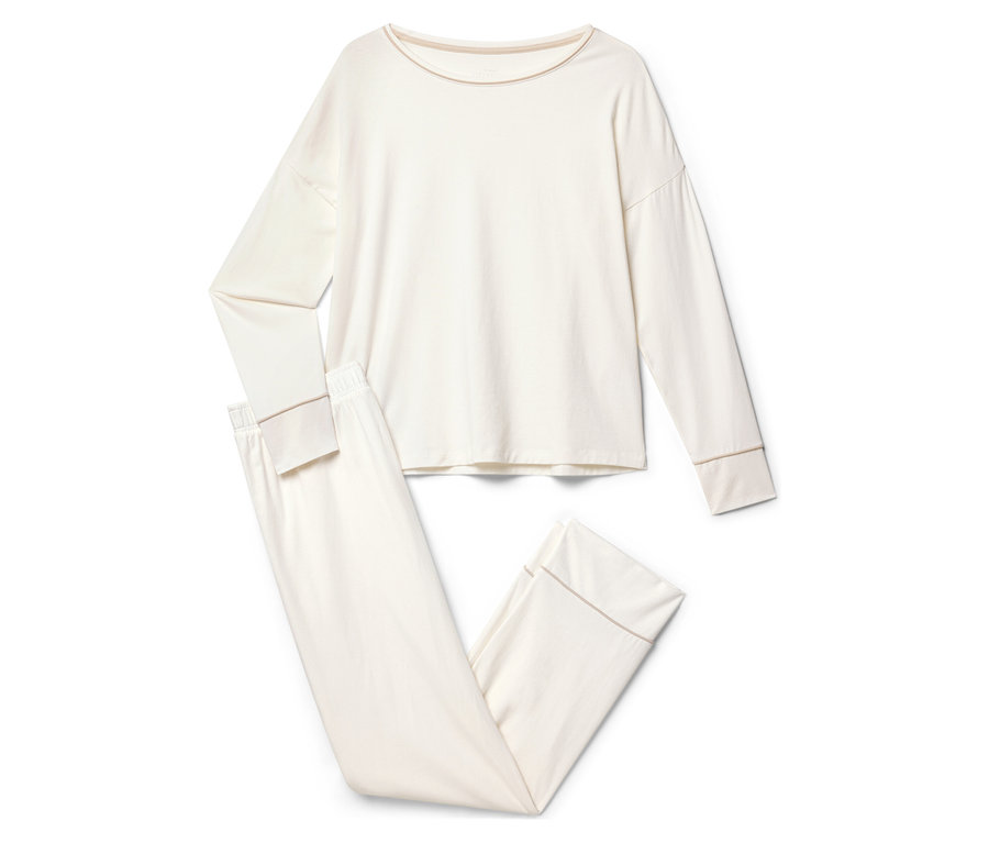 Ein cremefarbener Pyjama mit langen Ärmeln und Hosen liegt auf einem weißen Hintergrund.