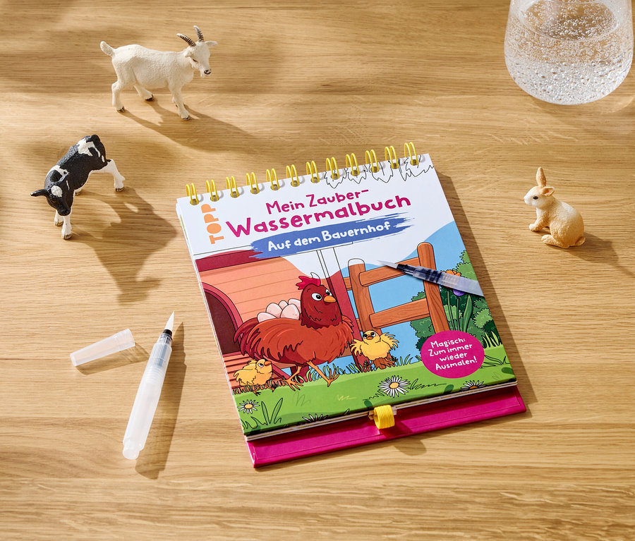 Auf einem Holztisch liegen ein Malbuch, ein Pinselstift, ein Wasserglas und Spielfiguren von Tieren.
