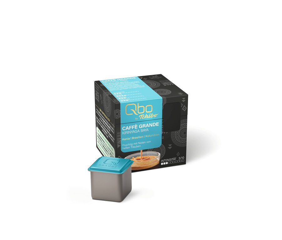 Ein grauer Karton mit blauer Banderole und weißer Schrift für Qbo by Tchibo Caffè Grande Kirinyaga Baya, daneben eine graue Kaffeekapsel mit blauem Deckel. Der Karton zeigt Herkunft (Kenia, Brasilien, Kolumbien), fruchtige Noten von hellen Trauben und Intensität 3/10.