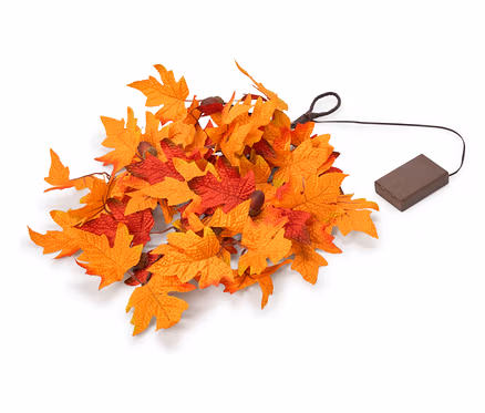 Ein Haufen künstlicher Herbstblätter in Orange und Rot, mit einem schwarzen Kabel, das zu einem braunen, rechteckigen Batteriefach führt.