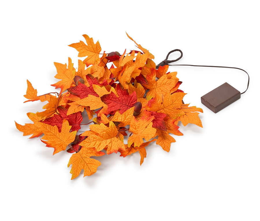 Ein Haufen künstlicher Herbstblätter in Orange und Rot, mit einem schwarzen Kabel, das zu einem braunen, rechteckigen Batteriefach führt.