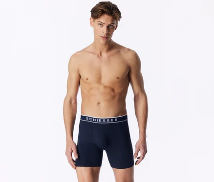 Ein oberkörperfreier Mann trägt dunkelblaue Boxershorts mit weißem SCHIESSER-Bund.