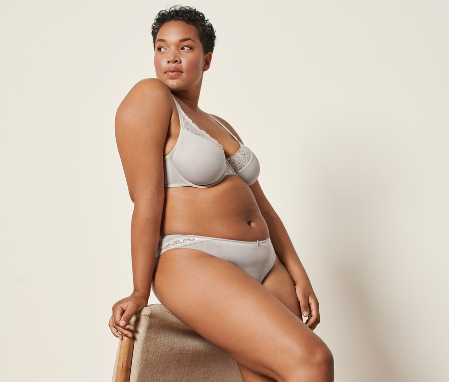 Eine Frau sitzt auf einem Stuhl und trägt mandelfarbene 2 Jazzpants und einen Bügel-BH.