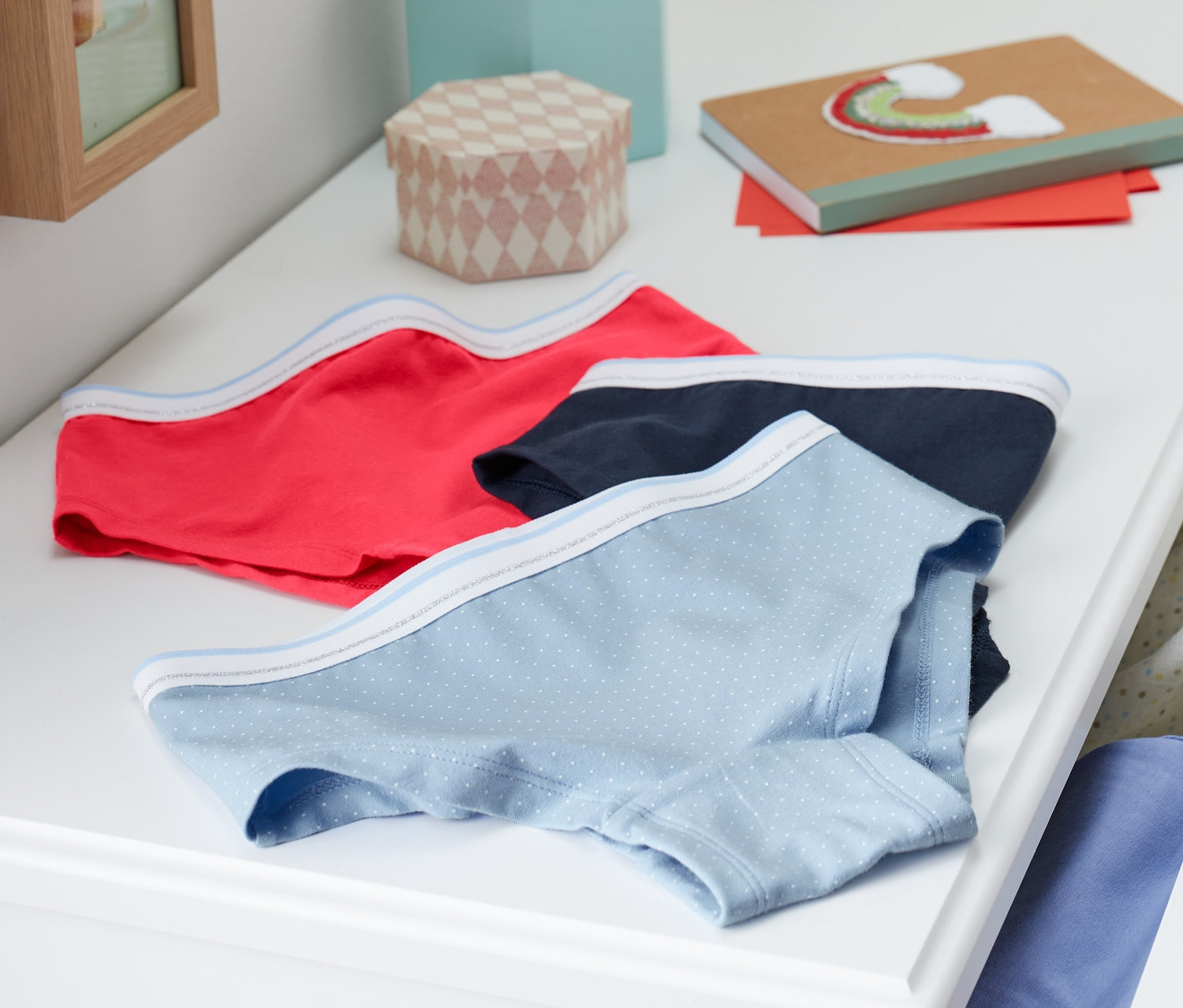 Drei Mädchen-Pantys mit Bio-Baumwolle liegen auf einer weissen Kommode.