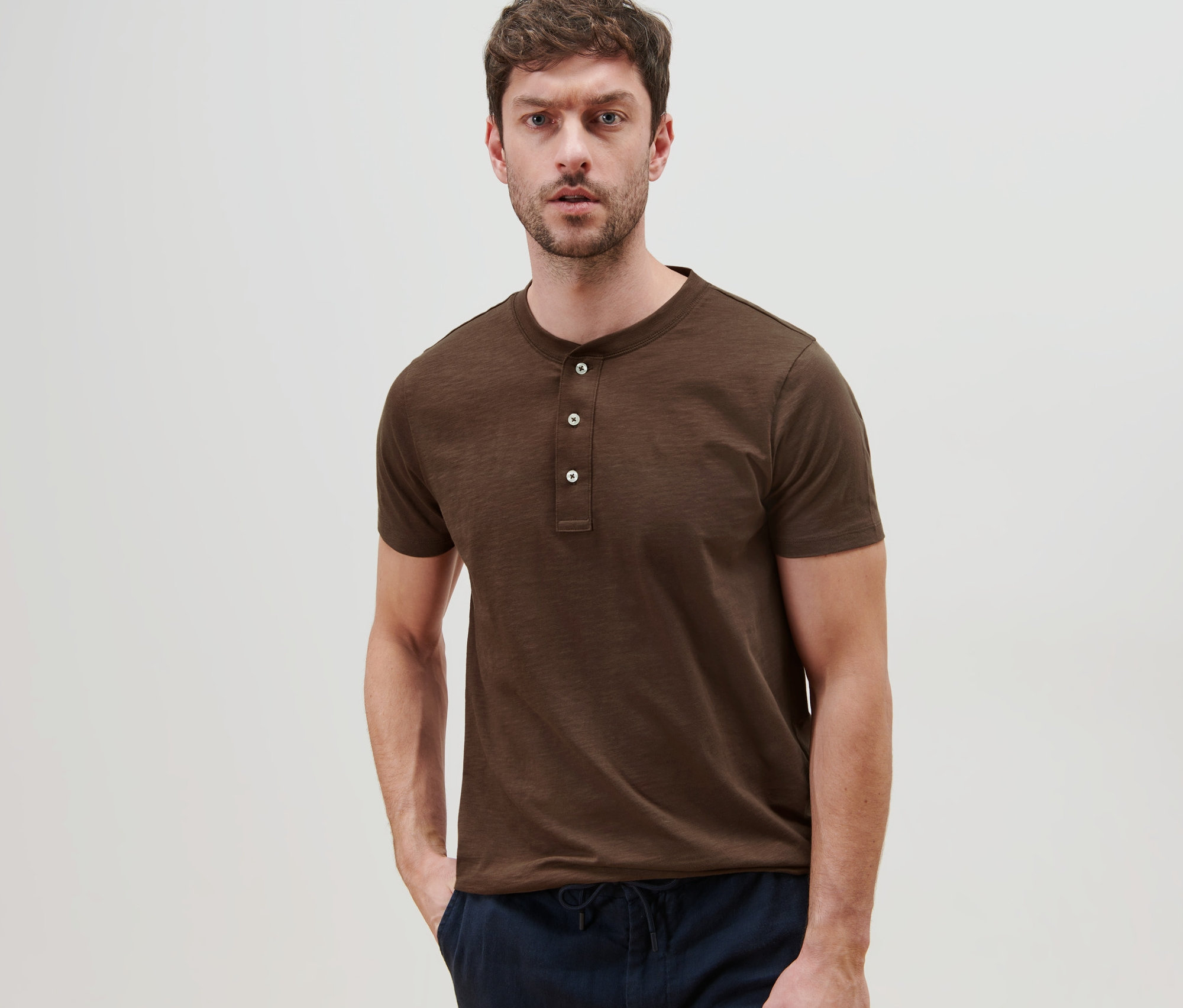 Mann posiert in einem braunen Kurzarm-Henley.