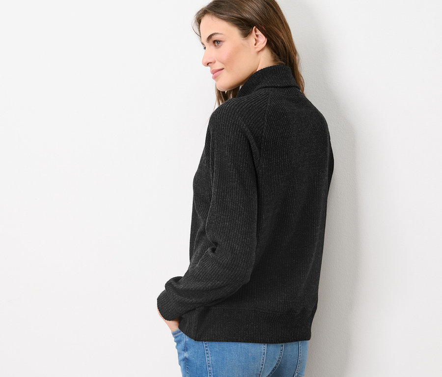 Eine Frau posiert seitlich in einem Sweat-Troyer und Jeans.